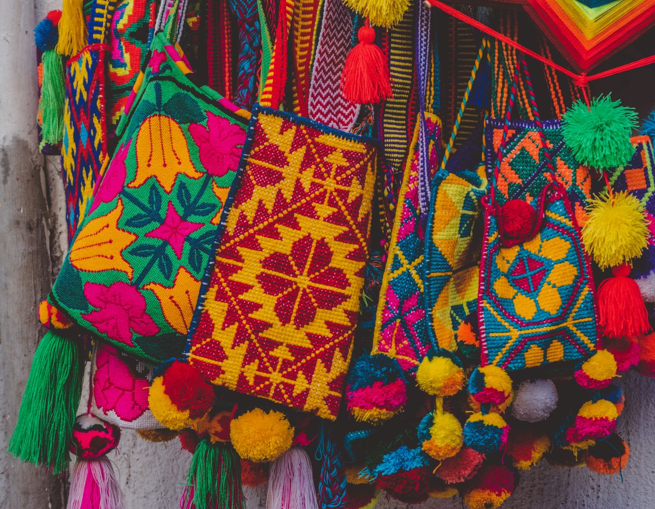 Colorful handmade knitted bags with tassels displayed as vibrant souvenirs.