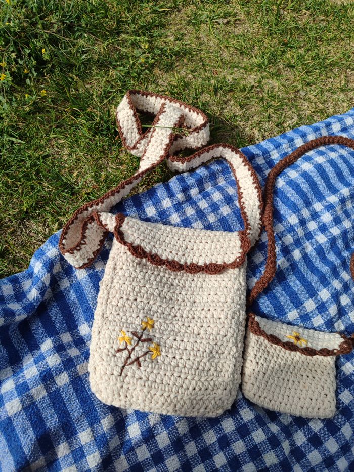 Handmade crochet bag on a blue checkered blanket in a grassy outdoor setting.