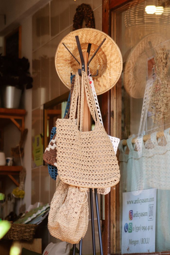 A variety of crochet bags hang on a hook rack outside a shop, exuding a rustic charm.