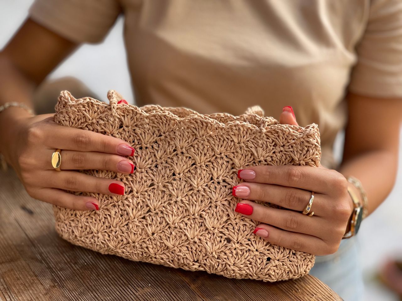 Close-up of a woman holding a handmade crochet handbag, showcasing intricate weaving and stylish design.
